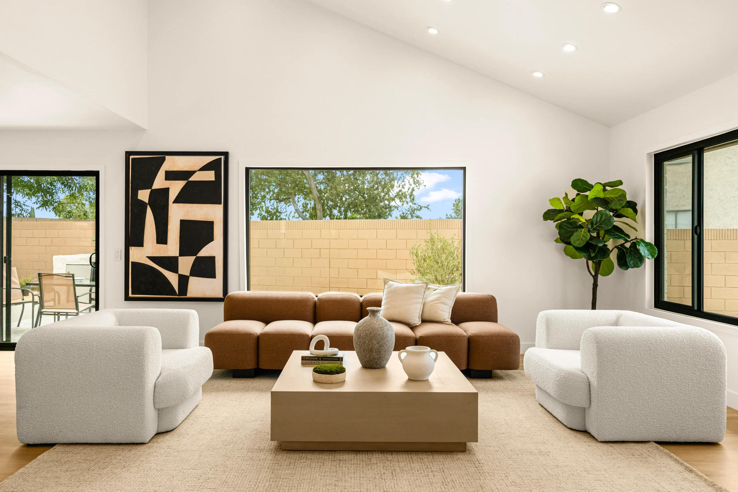 Modern Living Room Staging with Neutral, Warm Tones Professionally staged living room with a rust sectional and two cream swivel chairs